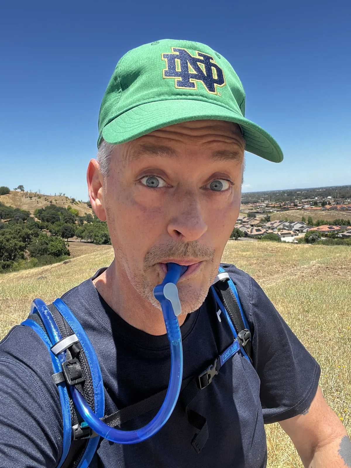 Gen X creator using a CamelBak water bottle during an active outdoor lifestyle moment.